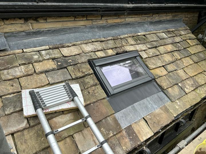 Rooflight set into a stone slate roof with lead soakers and apron
